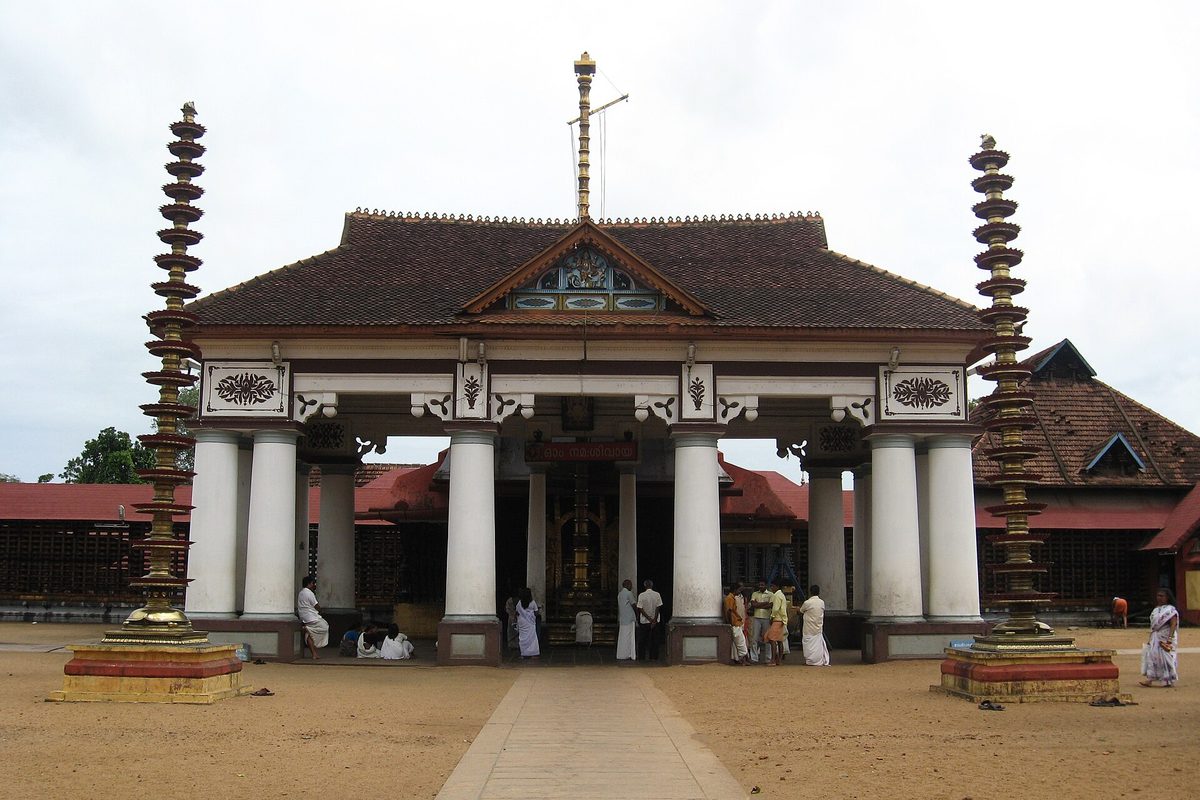 The gateway and tiered roof of Vaikom Mahadeva Temple, with visitors at the entrance.