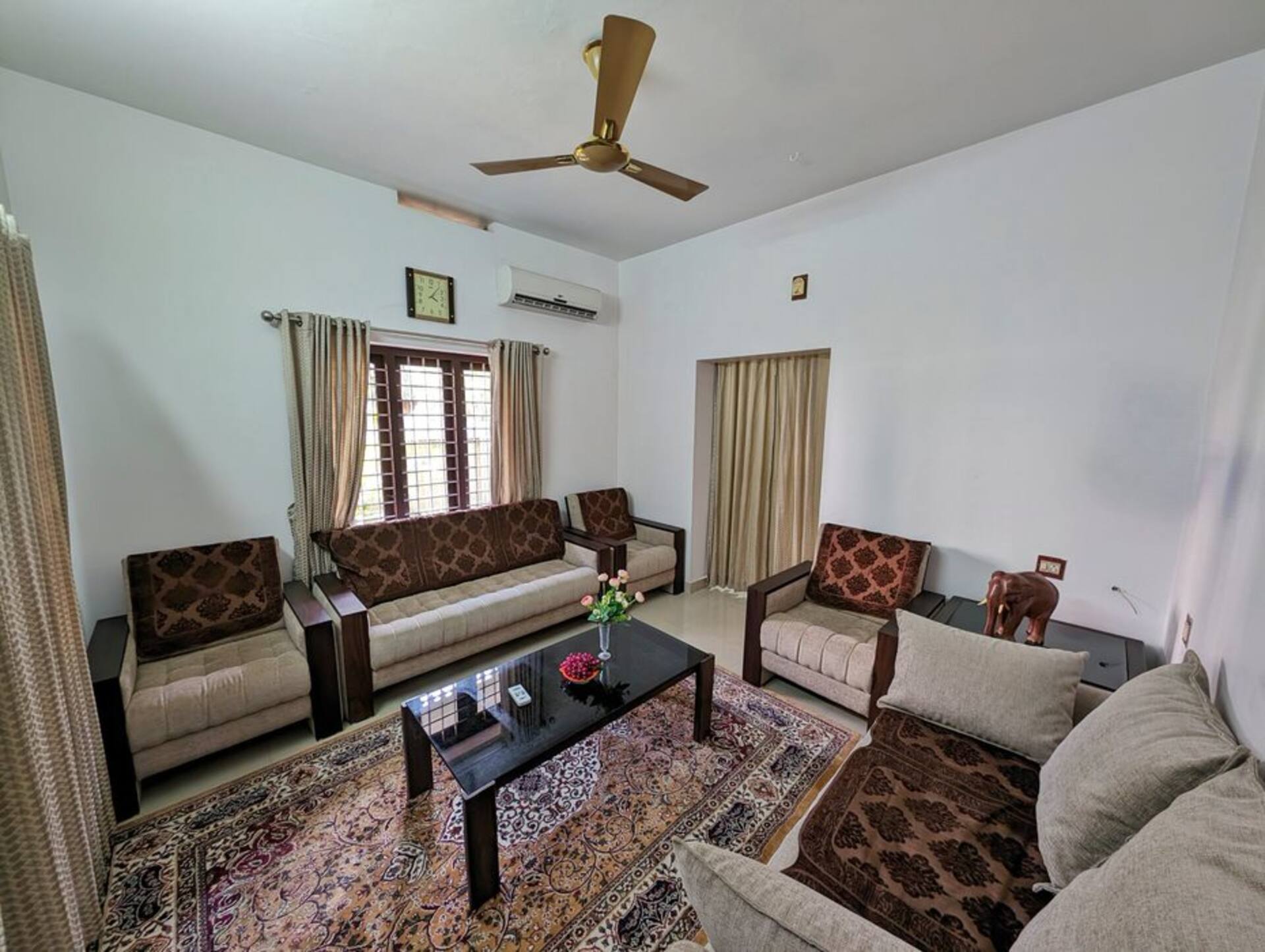 The common living room with sofas, teak furniture and daylight from the garden windows.